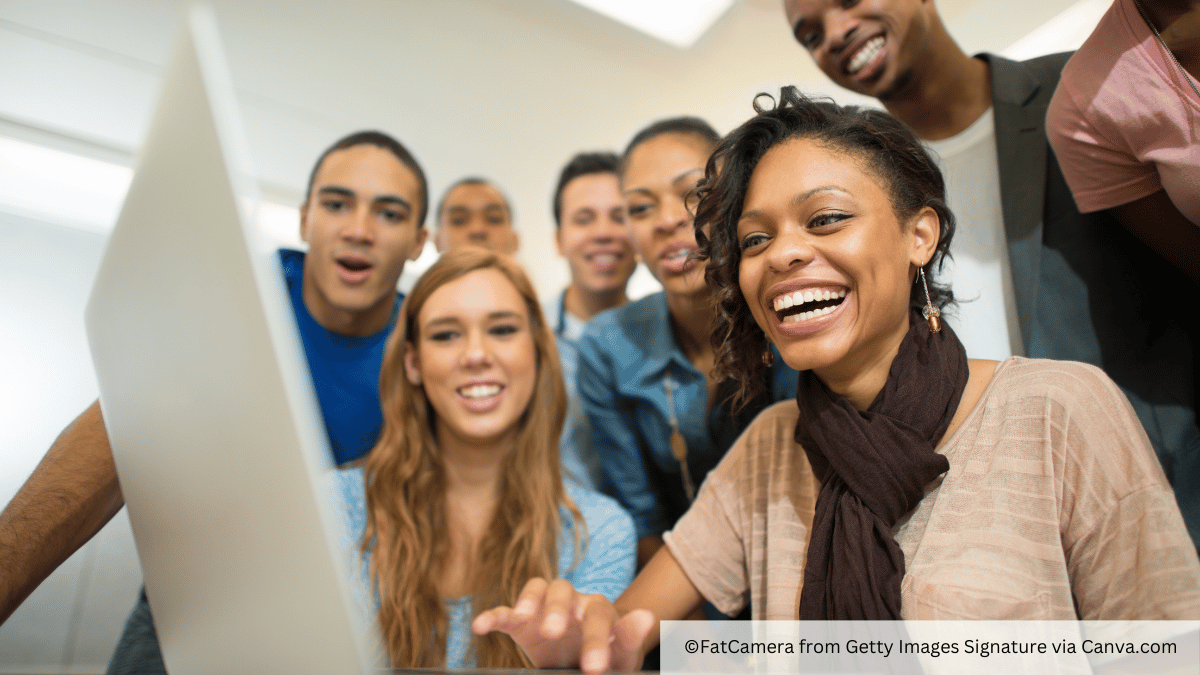 students at a computer together smiling