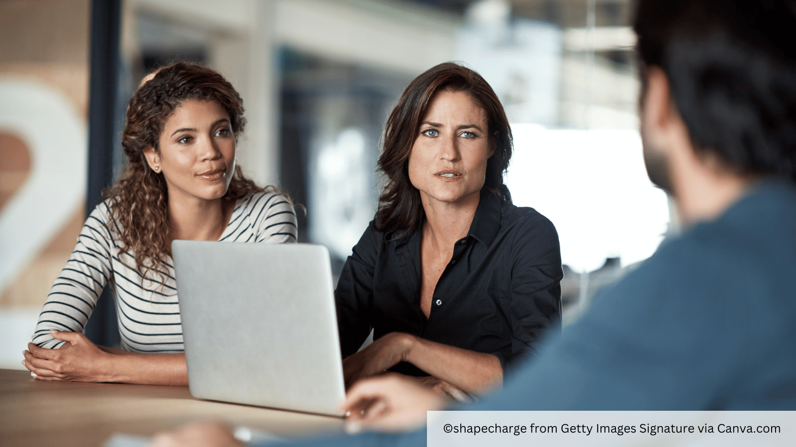two women looking sceptical speaking to a colleague 